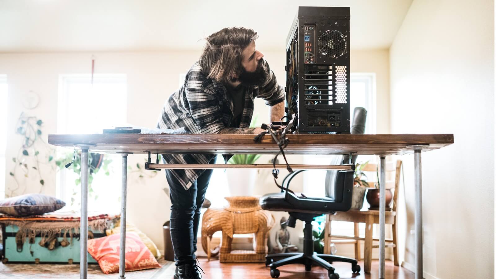 Man looking at plugging in cables to computer.